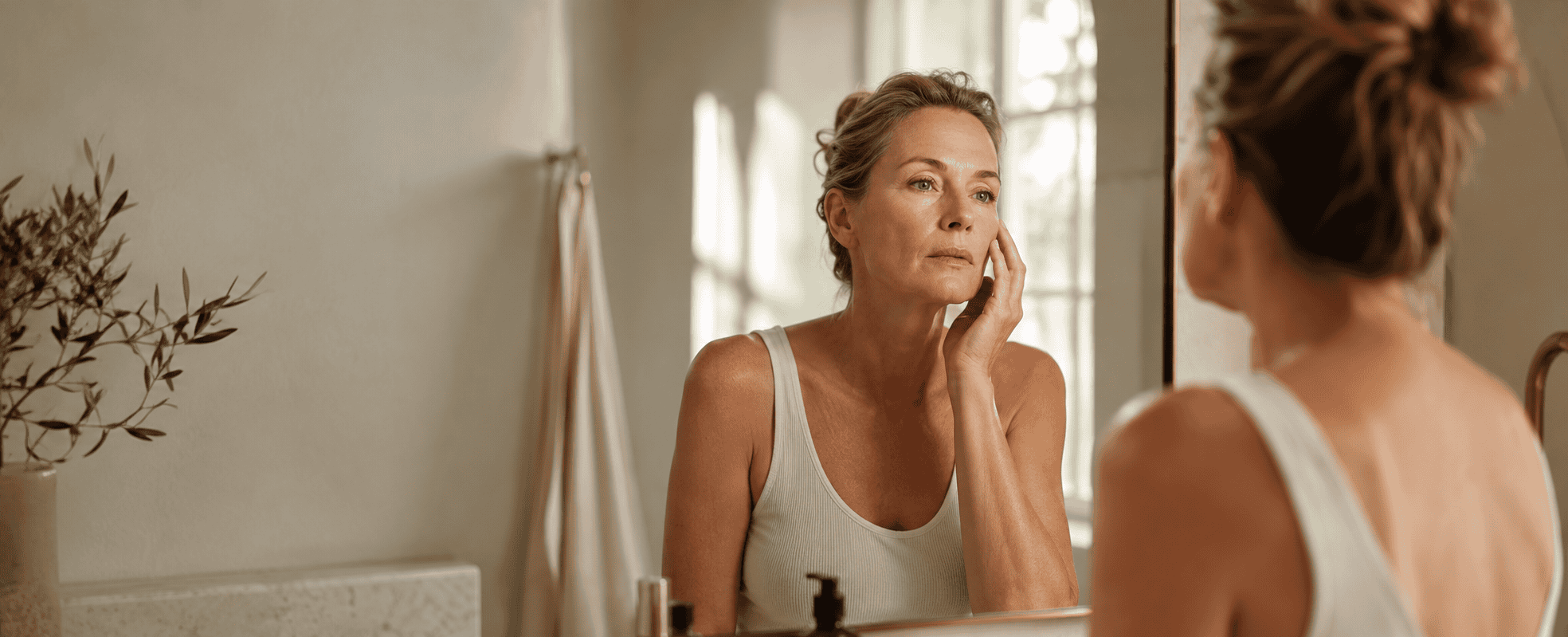 Woman in her mid-40s at a bathroom mirror in natural morning light